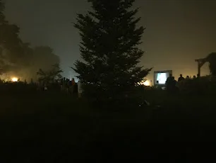 An outdoor movie screen glowing in the fog at Agamont Park in Bar Harbor at night