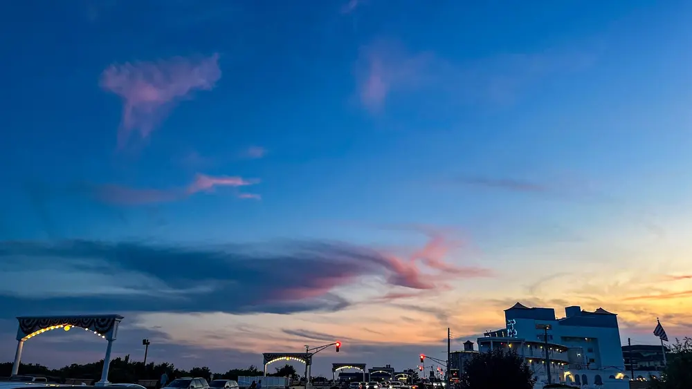 A wide pink and blue dusk sky over the lit arches of the Cape May Promenade with Convention Hall on the right