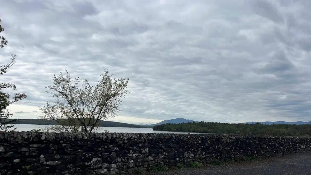 A low stone wall along the Ashokan Reservoir with the Catskill peaks and a heavy grey sky beyond