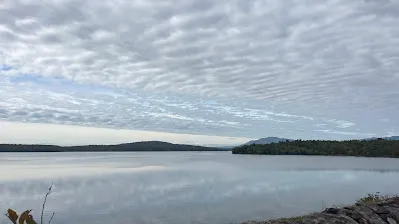 The calm surface of the Ashokan Reservoir under a mackerel sky, low green hills on the far shore