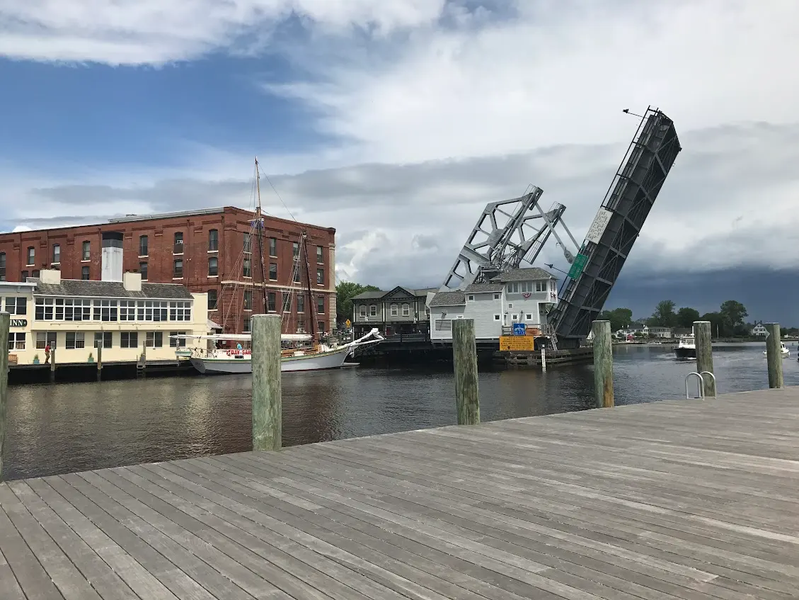 The Mystic River Bascule Bridge raised open, its roadway tilted into the sky between the counterweight towers, a schooner moored alongside