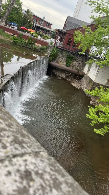 A small waterfall on the creek running through downtown New Hope Pennsylvania, with outdoor cafe seating along the bank