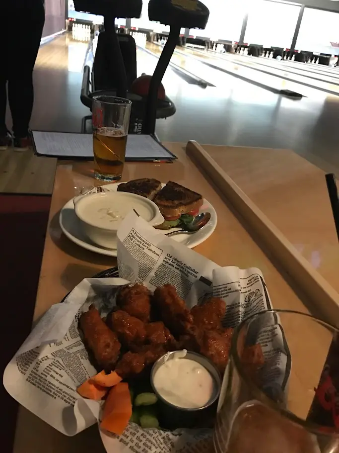 A lane of candlepin bowling with a basket of wings and a beer on the table in the foreground