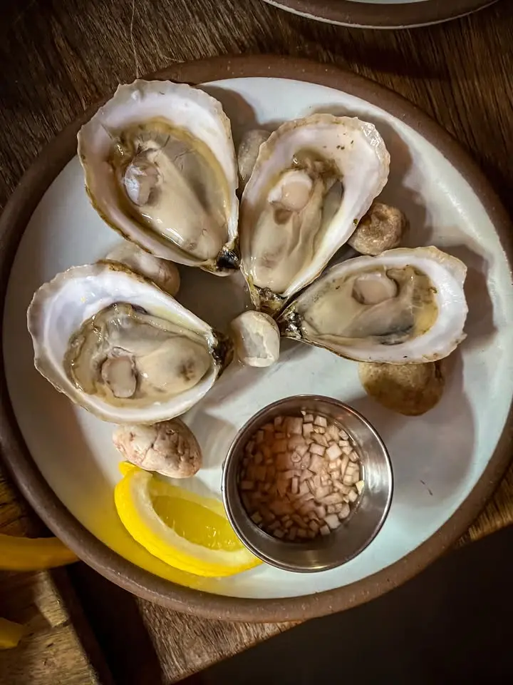A plate of freshly shucked local oysters with lemon and mignonette on a Nantucket table