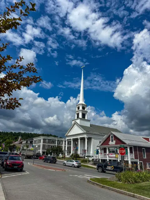 The tall white spire of the Stowe Community Church rising over Main Street against a blue sky full of clouds